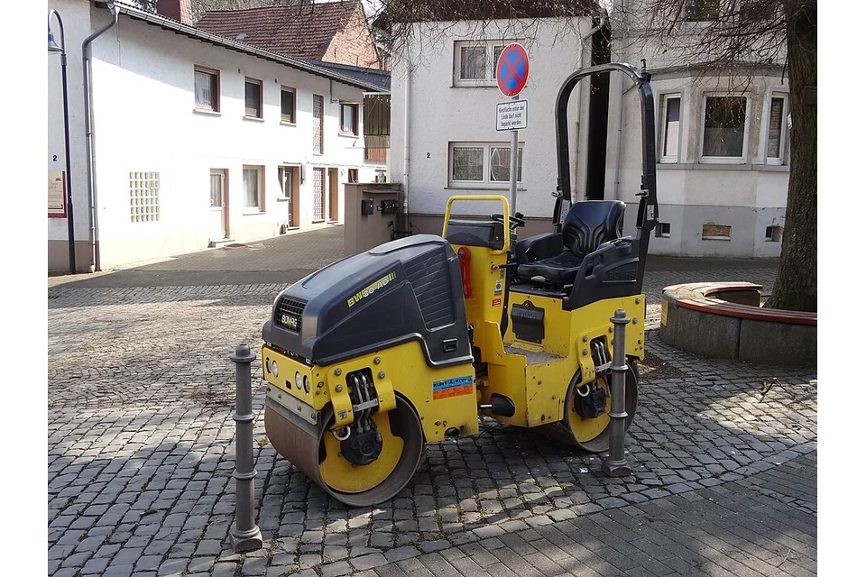 Cilindro tandem BOMAG amarelo, com dois rolos de aço e lugar de condução.